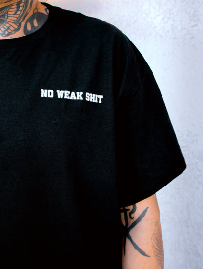 Black t-shirt with 'NO WEAK SHIT' text worn by a person with tattoos on a light gray background